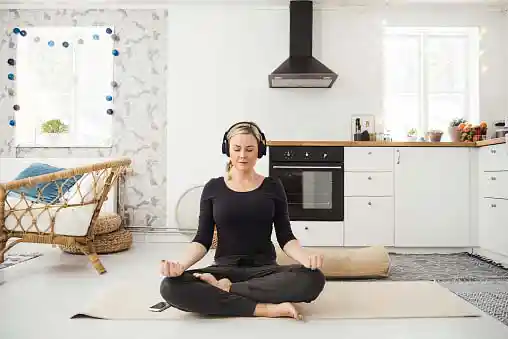 mature woman meditating in her house while listening to soothing music